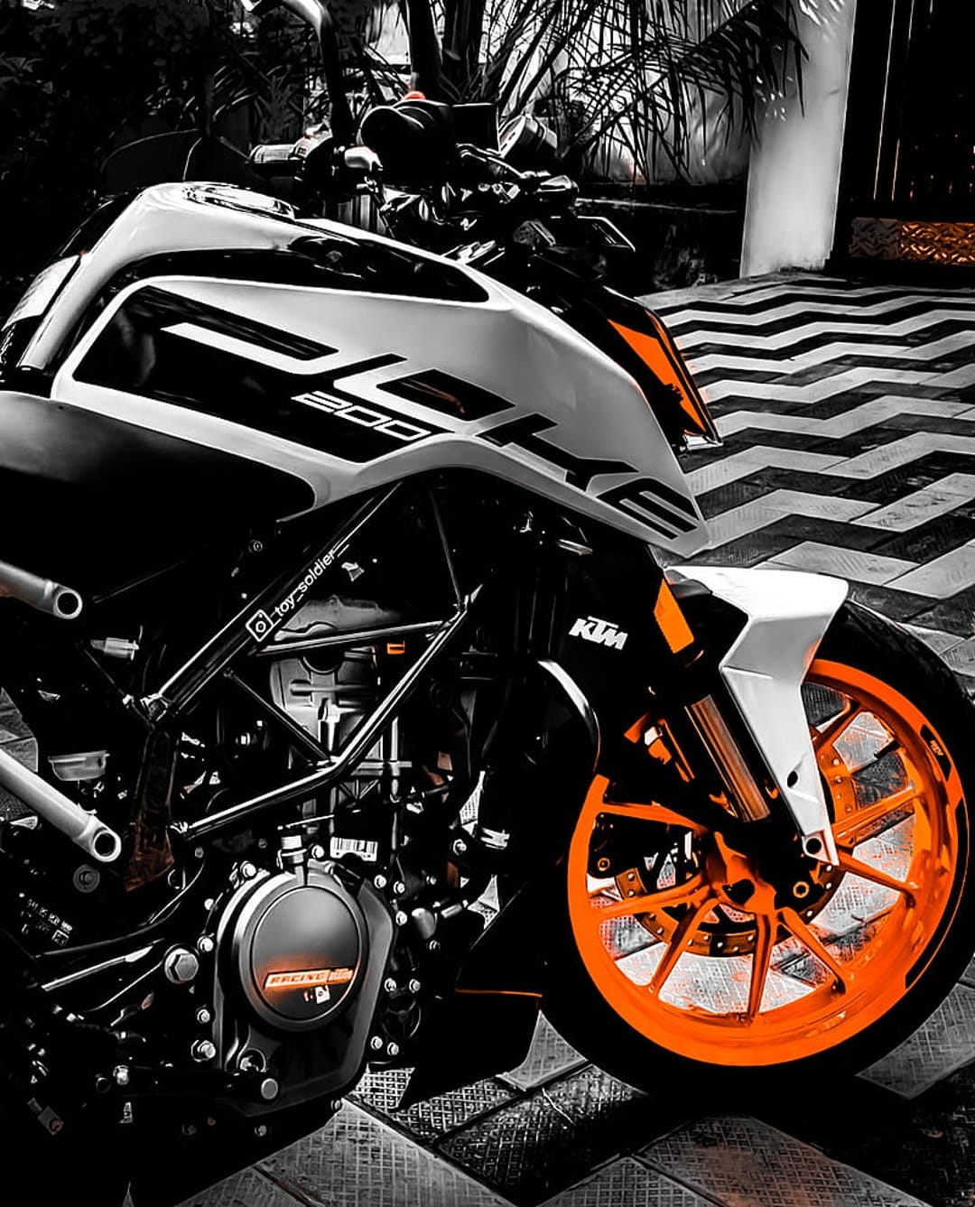 KTM 200 Duke motorcycle featuring orange rims and white bodywork parked on a black and white zigzag patterned floor.
