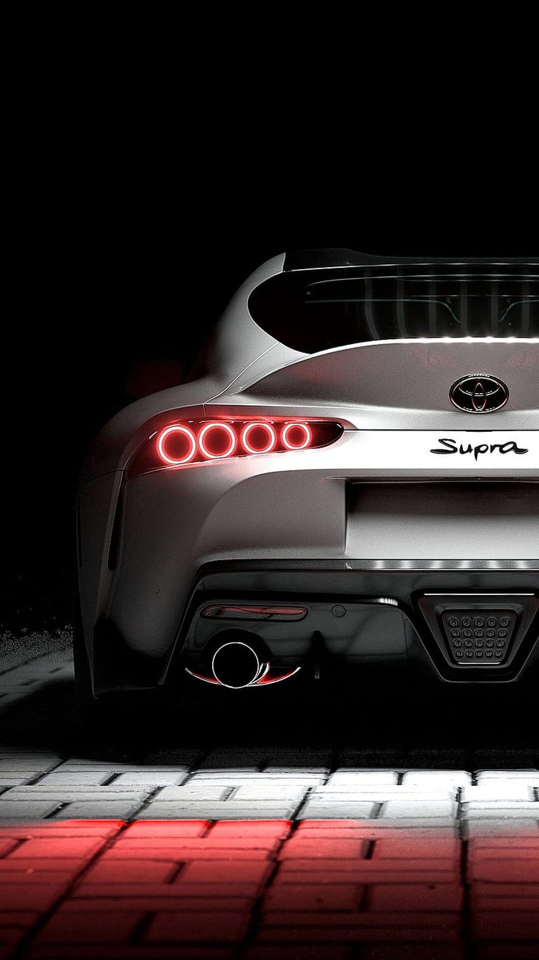 White Toyota Supra rear with glowing red circular taillights and reflective ground on a dark black background.