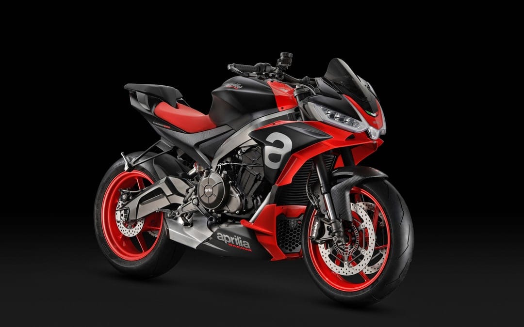 Aprilia Tuono 660 motorcycle with red wheels and seat against a solid black studio background.