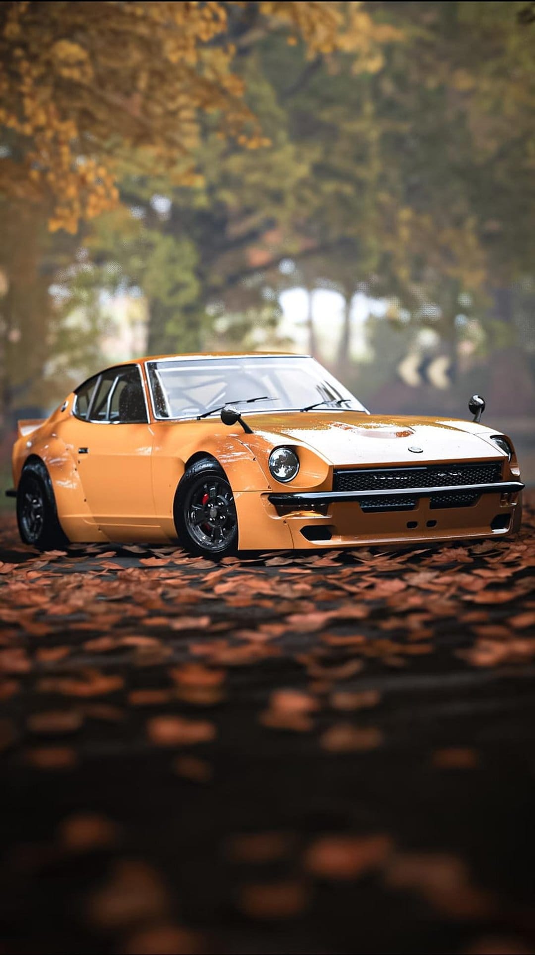 Orange Datsun 240Z with widebody fenders parked on a carpet of fallen orange autumn leaves in a sunlit forest.