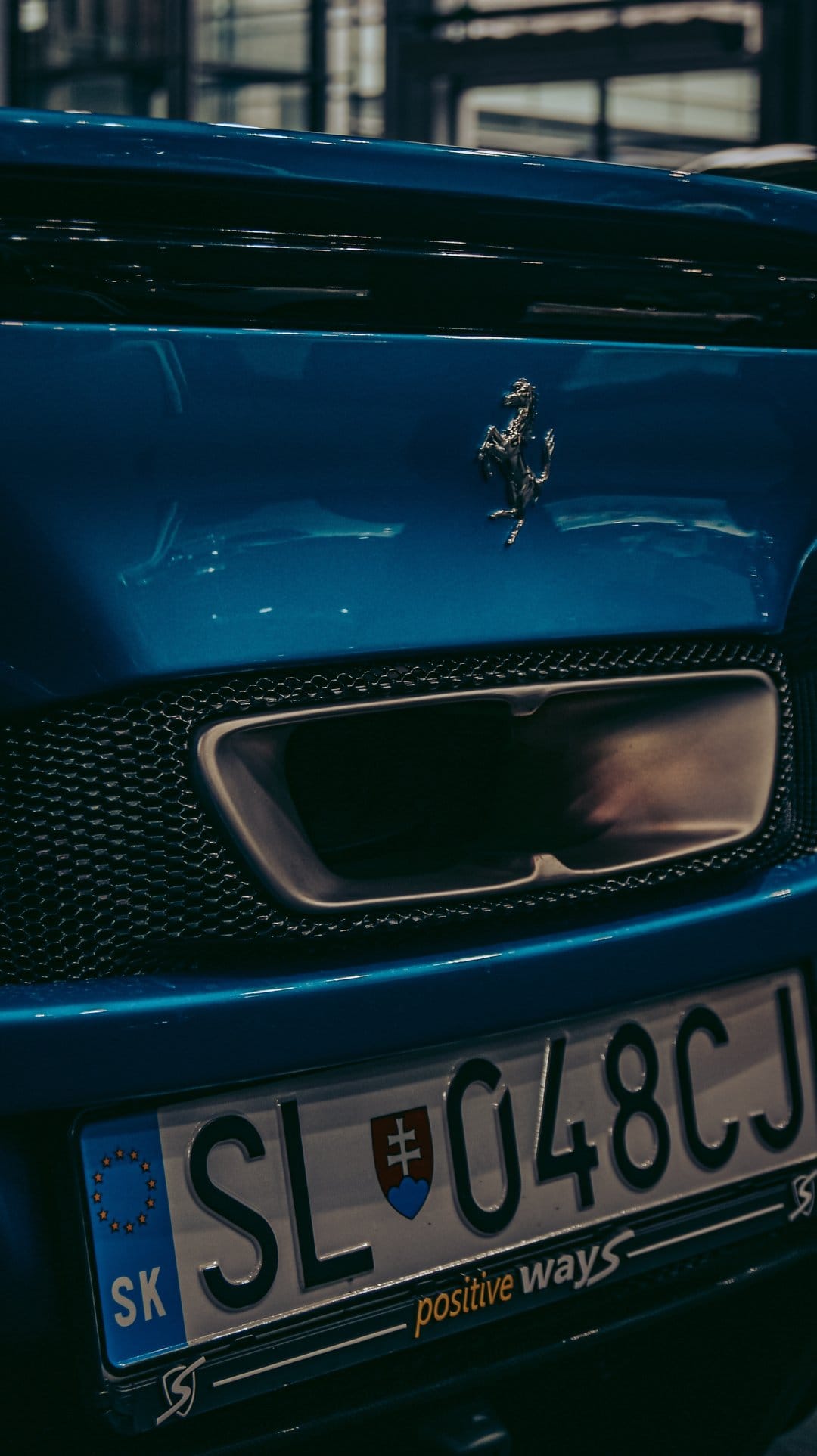 Blue Ferrari rear bumper with a silver prancing horse logo, exhaust vent, and Slovakian license plate SL 048CJ.