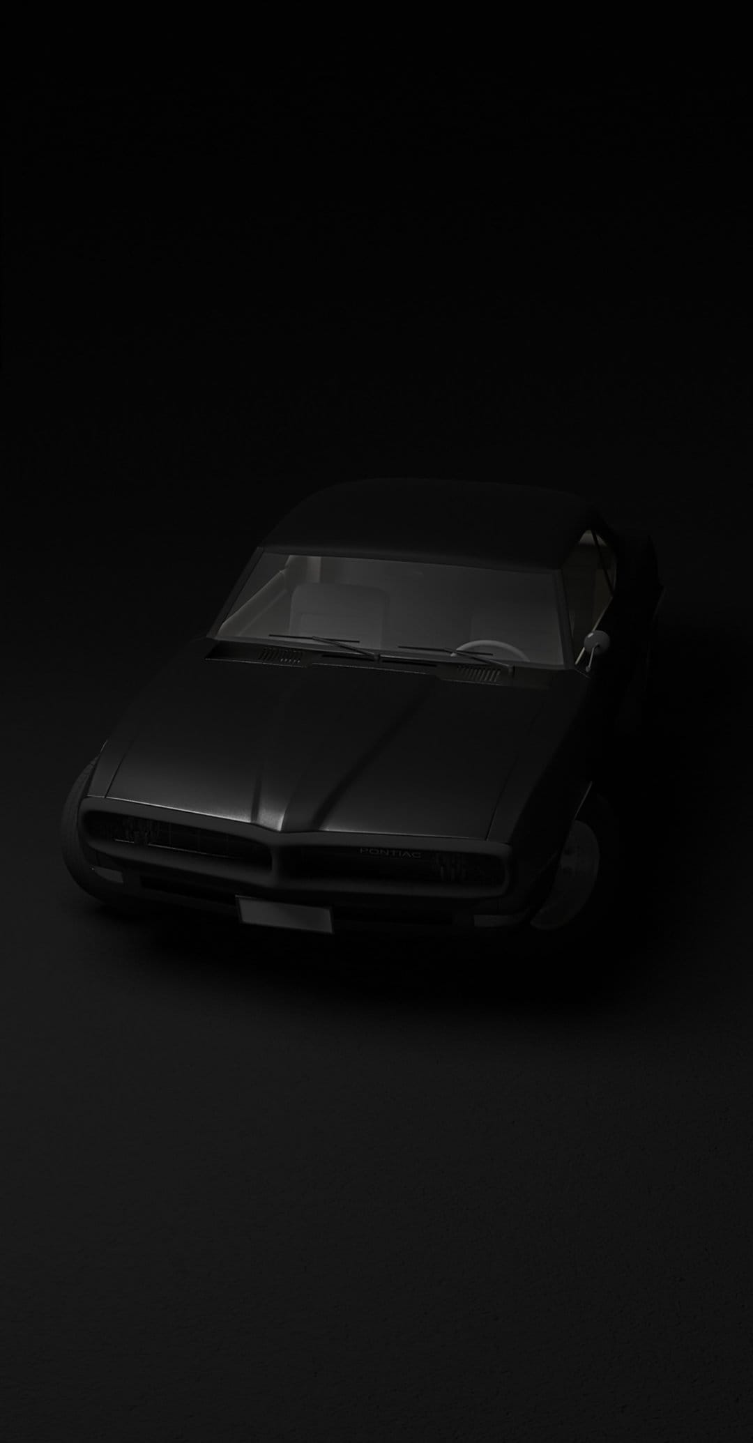Black sports car front view with circular headlights and a grille visible against a solid dark background.