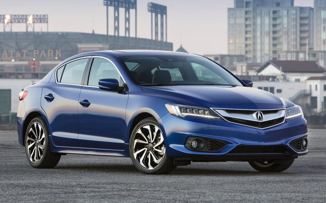 Blue Acura ILX luxury sedan parked on asphalt with a city stadium and buildings in the soft sunset background.