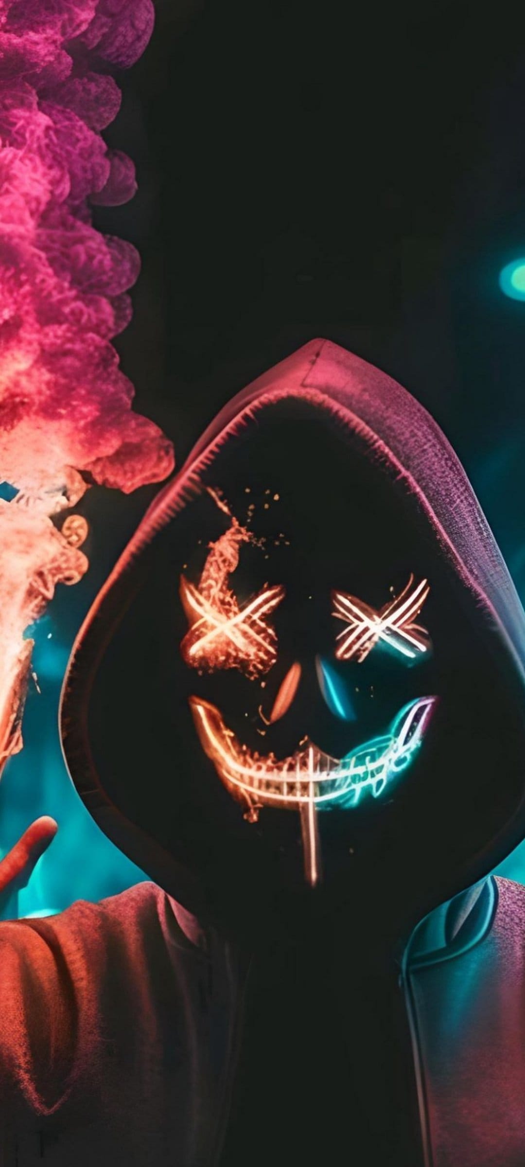Masked person wearing a black hoodie and a glowing pink neon mask surrounded by vibrant orange and pink smoke.