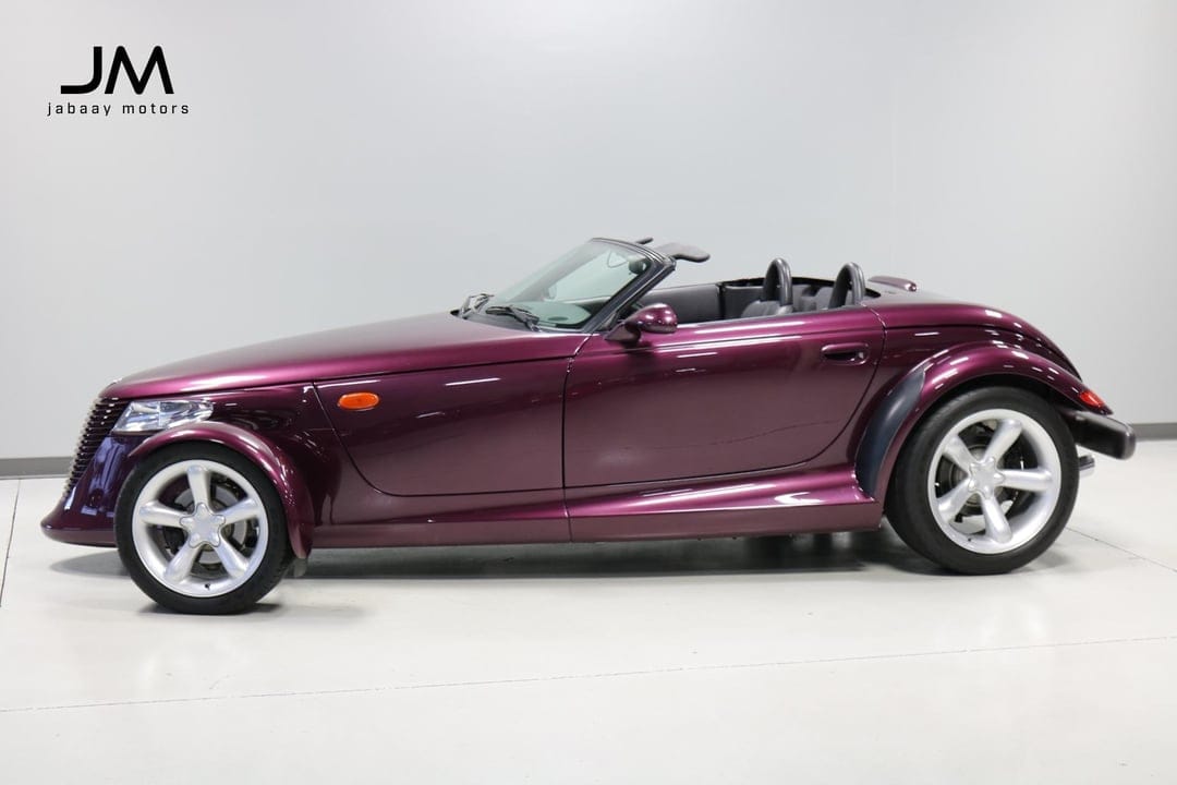 Metallic purple Plymouth Prowler convertible with silver wheels shot in profile in a bright white studio.
