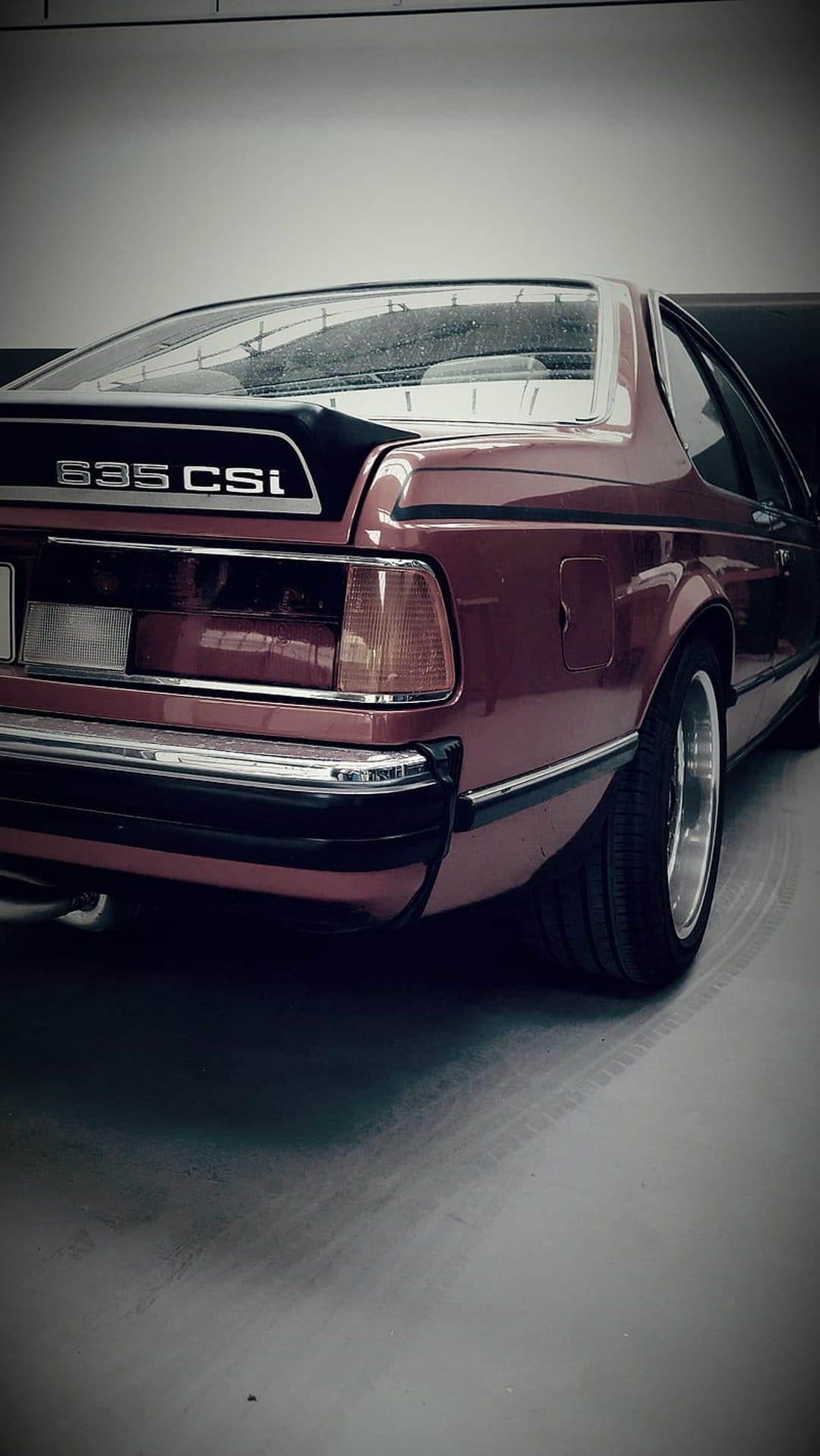 Maroon BMW 635 CSi rear-quarter view highlights metallic paint, chrome trim, and classic alloy wheels.