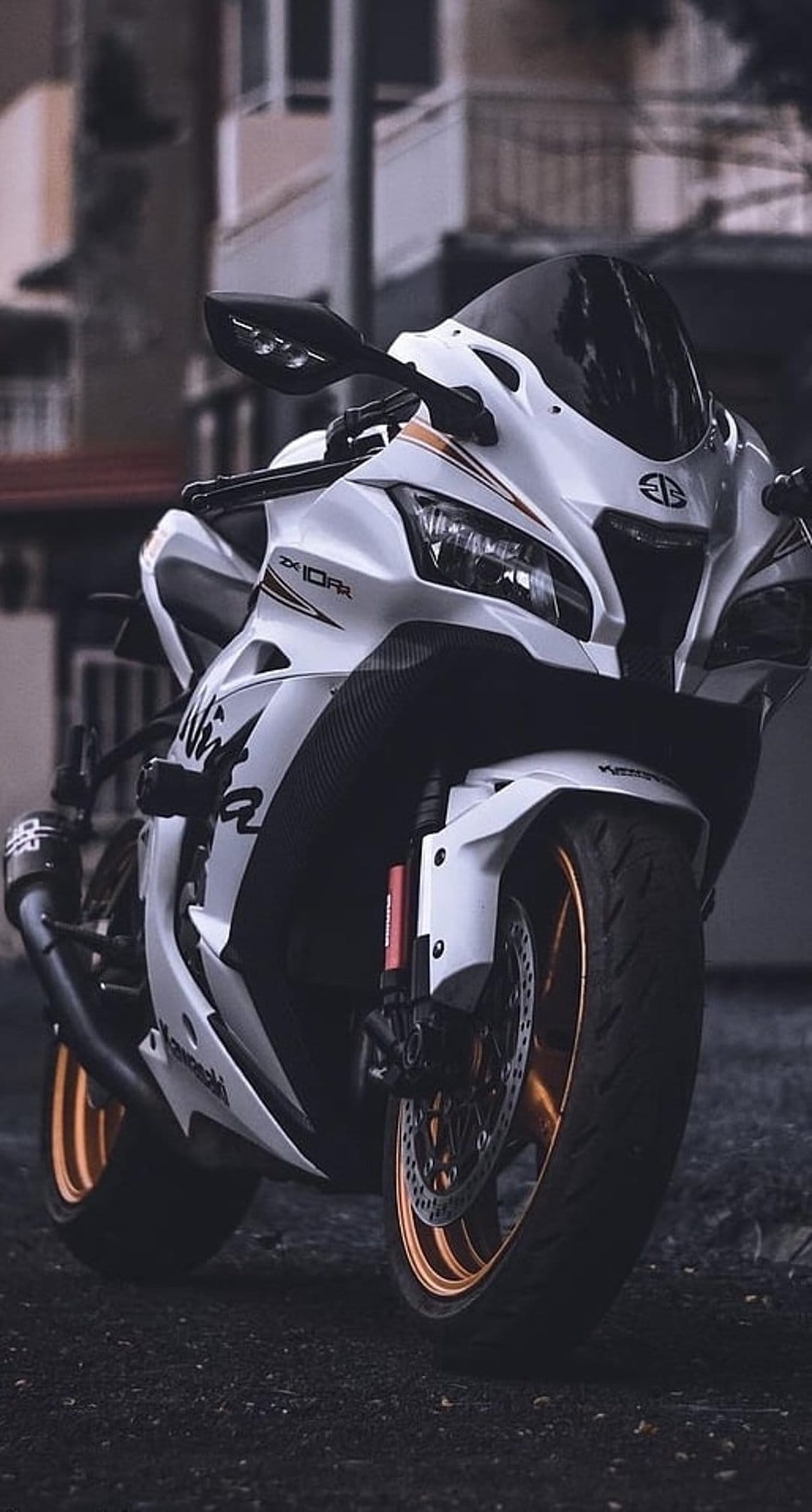 White Kawasaki Ninja ZX10RR sportbike with orange wheel rims and headlights viewed from a low front angle.
