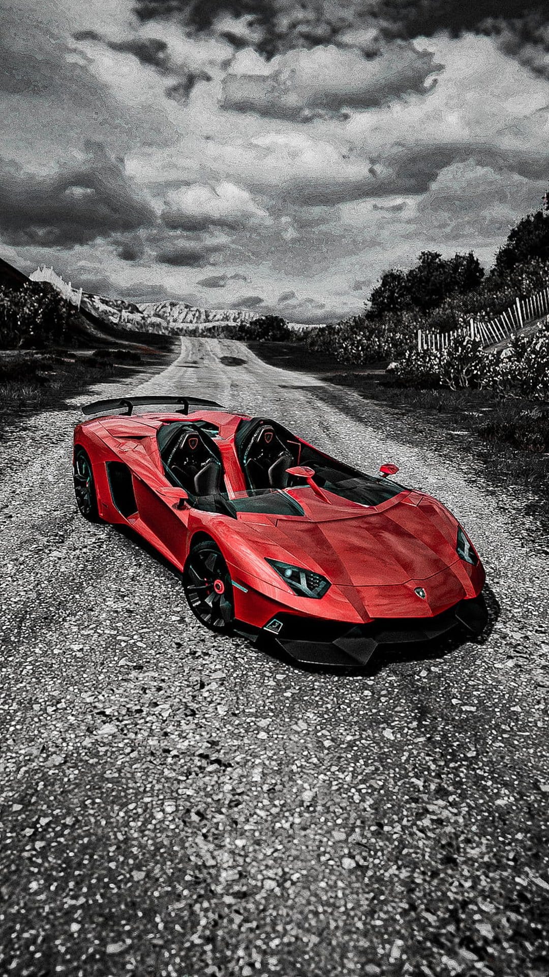 Red Lamborghini Aventador Roadster parked on a textured gravel path beneath a dramatic, cloudy sky.