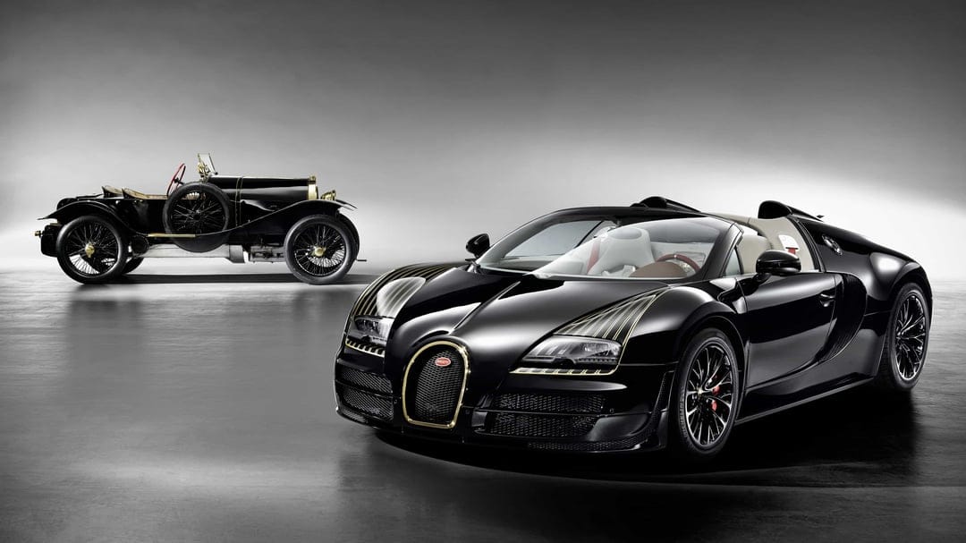 Modern black Bugatti hypercar with gold accents and a vintage race car in a minimalist grey studio.