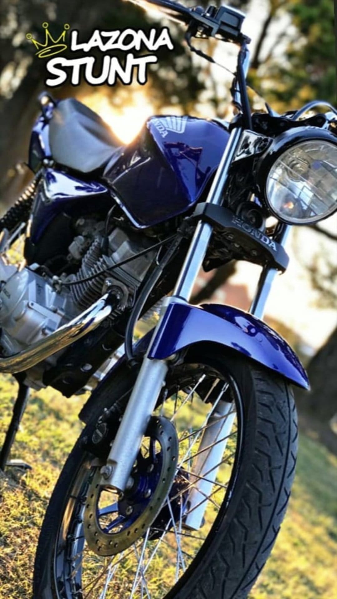 Blue Honda stunt bike featuring LAZONA STUNT graphics and a crown emblem on the fuel tank in a low-angle shot.