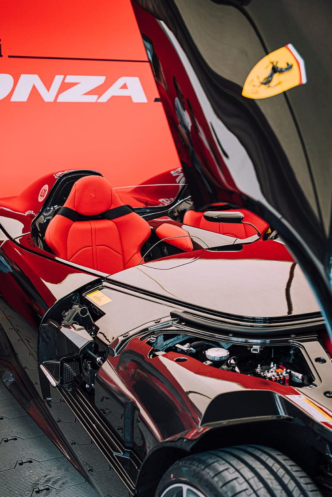 Ferrari Monza SP1 red leather bucket seats and exposed V12 engine compartment viewed from a vertical angle.