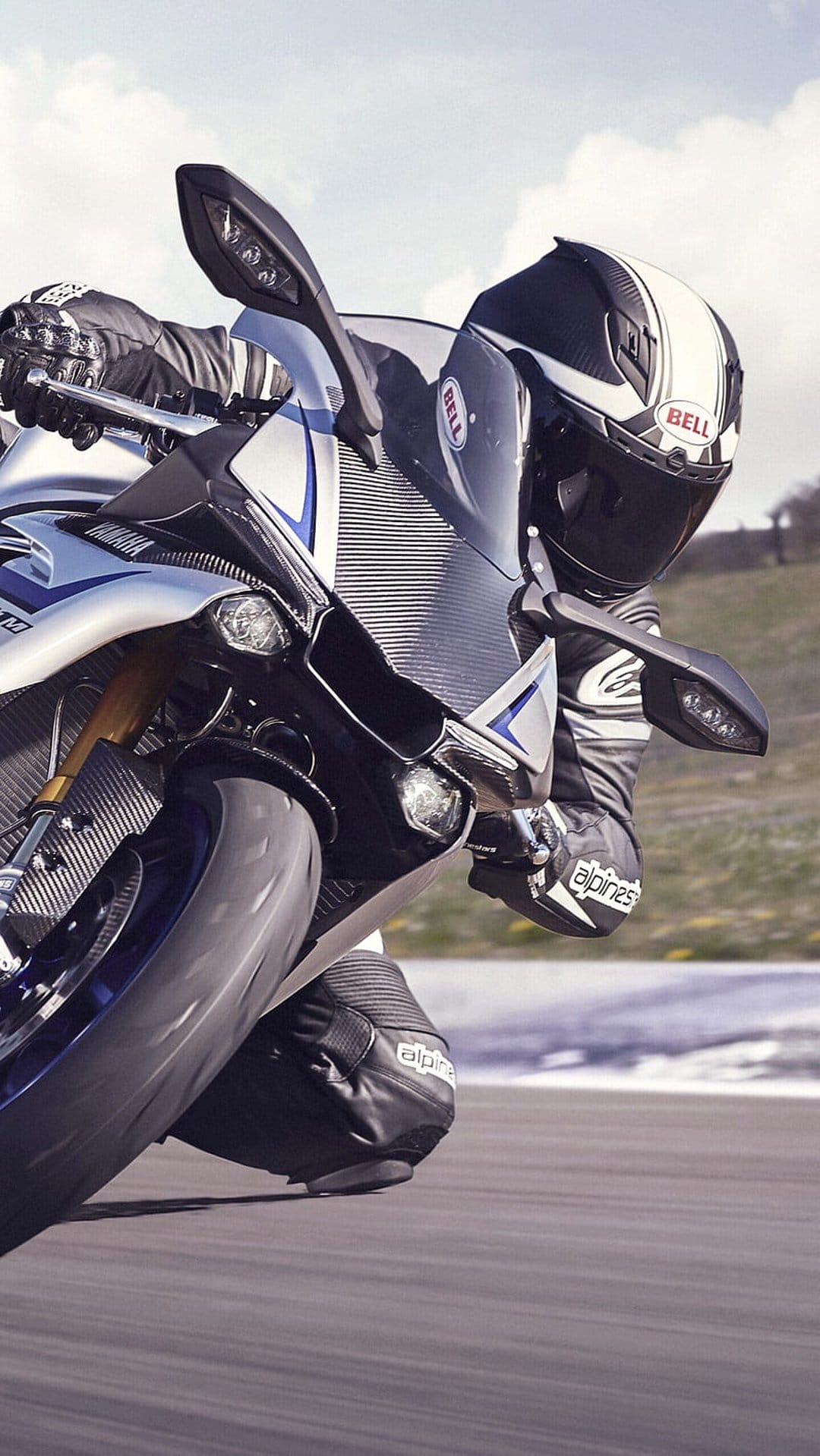 Motorcycle racer in leather gear leans a sportbike deep into a track turn with focused front wheel detail.
