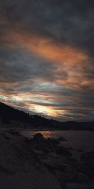 Sunset, Shoreline, Rocks, Beach, Nature, Clouds, Dusk, Twilight, Coastal, Landscape, Water, Orange, Sky, Serene, Tranquil, Outdoors, Horizon, Dark, Peaceful, Contemplative