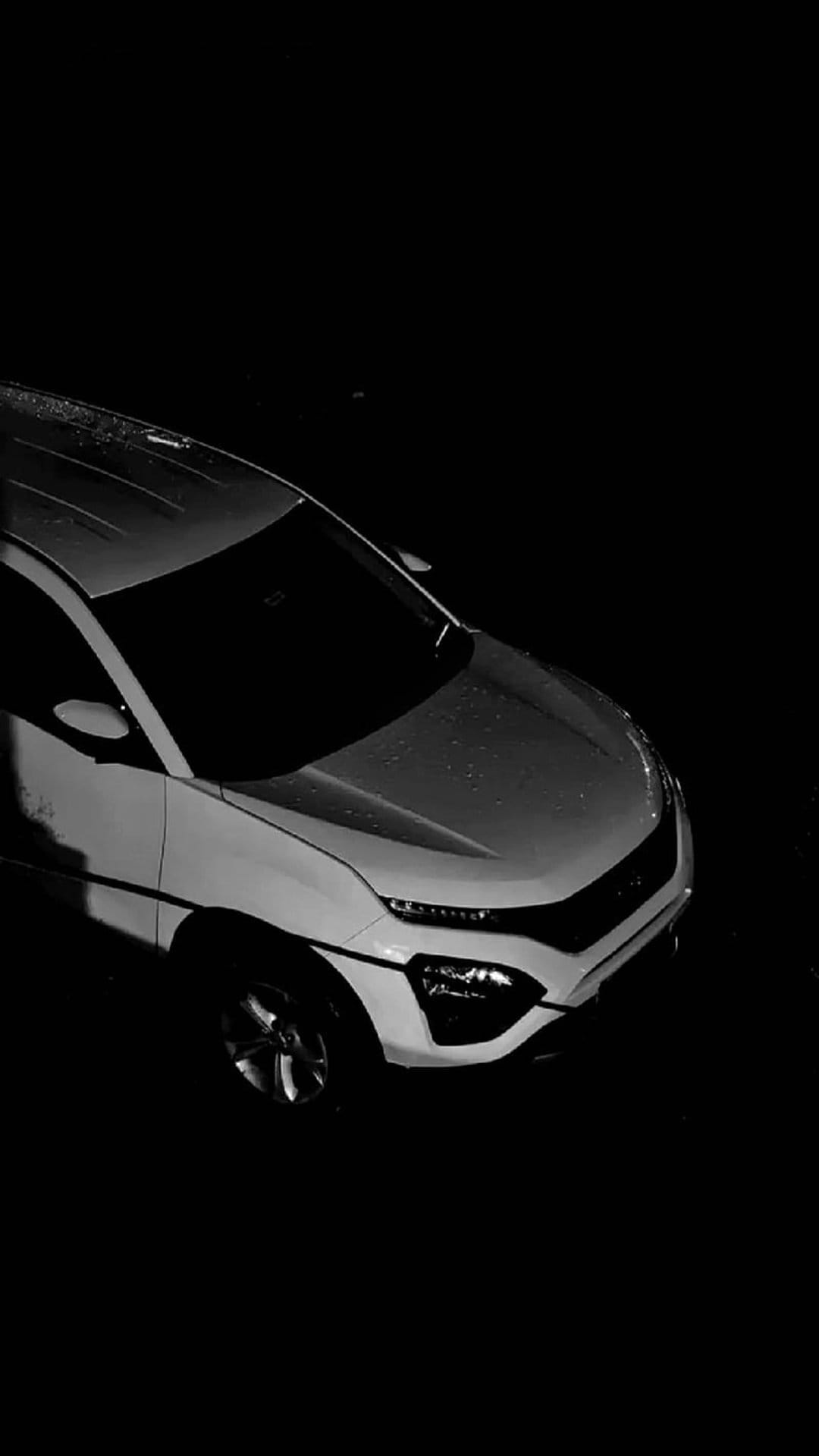 White SUV hood covered in glistening raindrops during a rainy night, viewed from a high-angle monochromatic perspective.