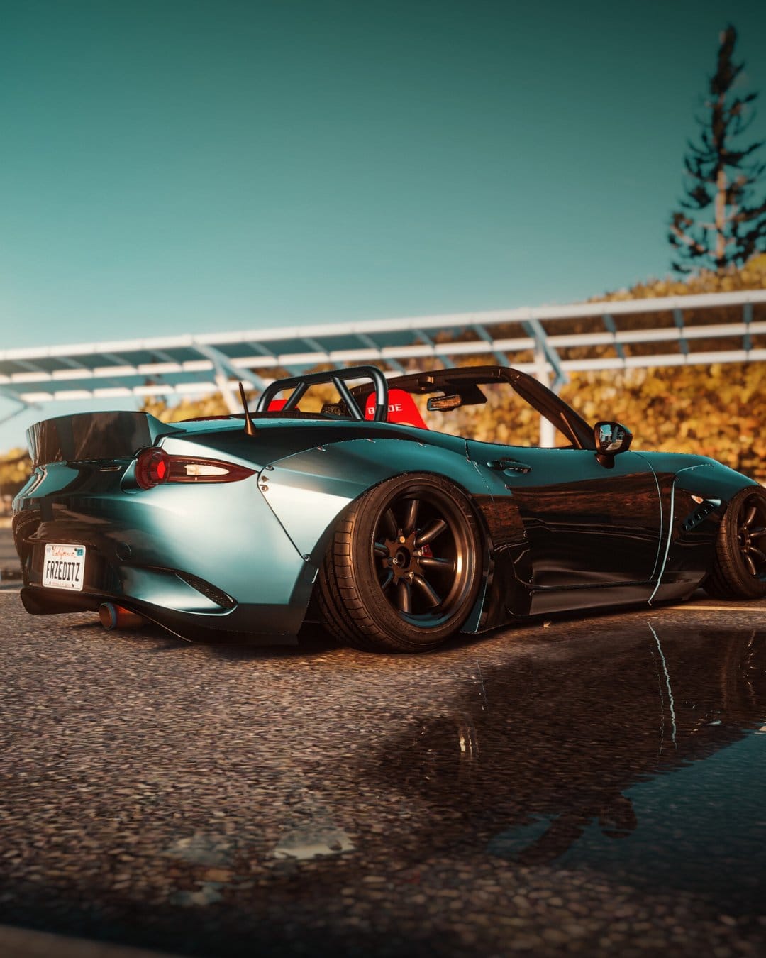Teal widebody Mazda MX-5 Miata parked on wet pavement with a reflection under a clear cinematic sky.