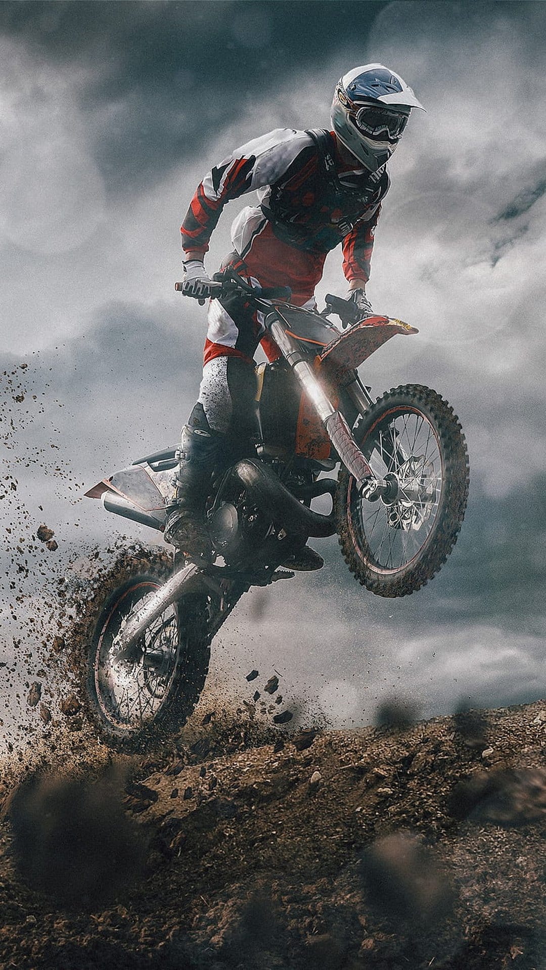 Motocross rider soaring mid-air on a dirt bike over a dusty track under a dark, dramatic, and cloudy sky.