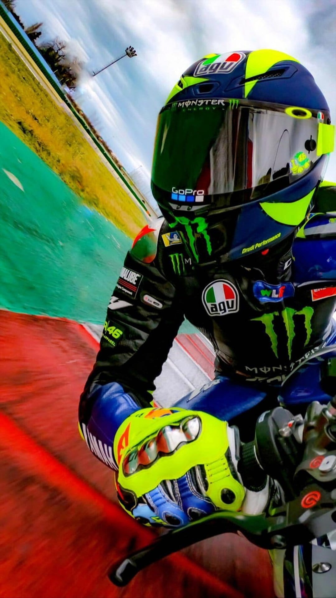 Valentino Rossi in a yellow AGV helmet leans a racing motorcycle into a high-speed turn on a blurred track.