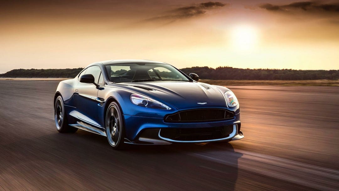 Blue sports car driving fast on a track under a golden sunset sky with motion blur and warm lighting.