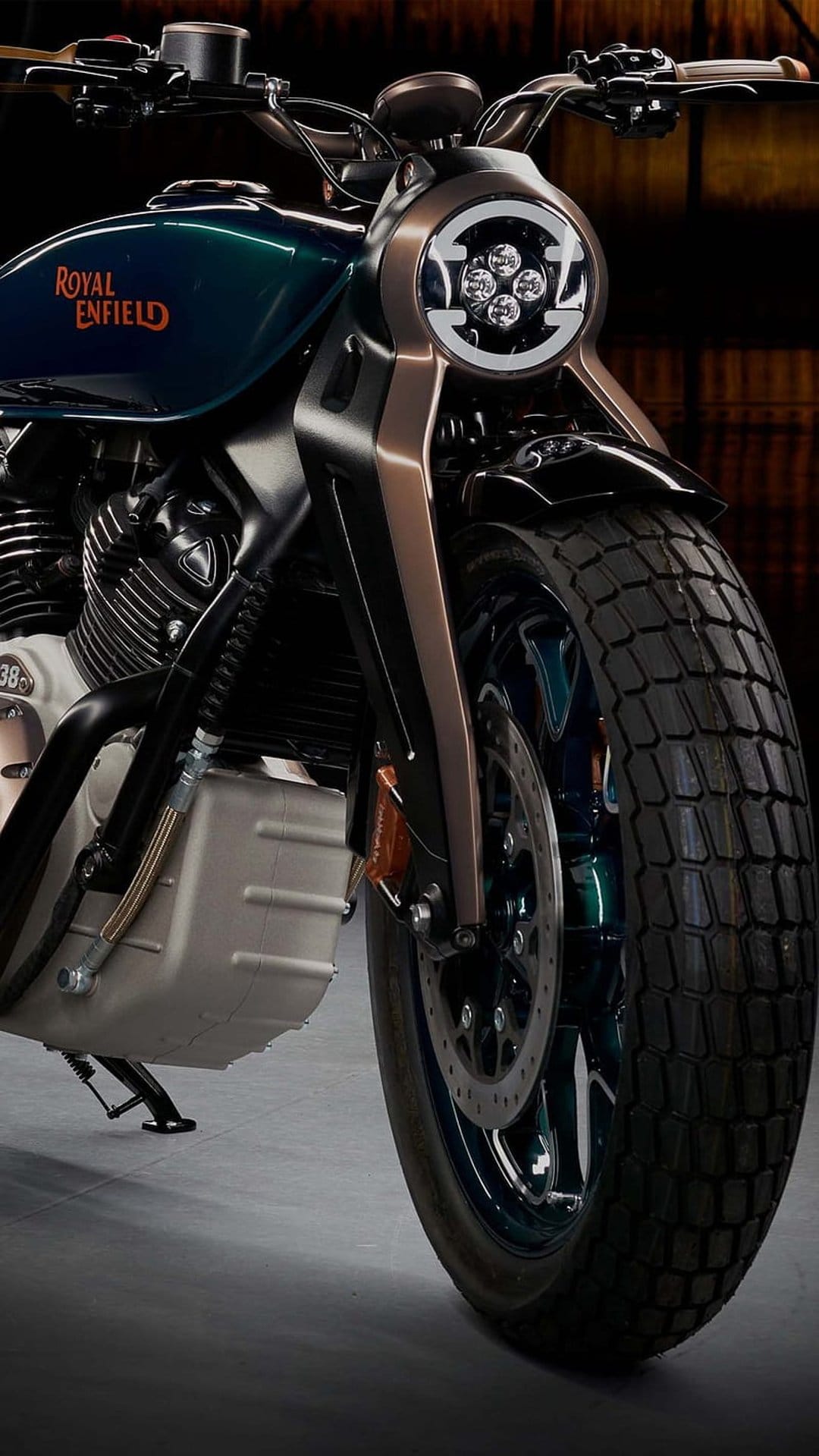 Royal Enfield motorcycle front end with a round LED headlight, bronze forks, and a dark green fuel tank.