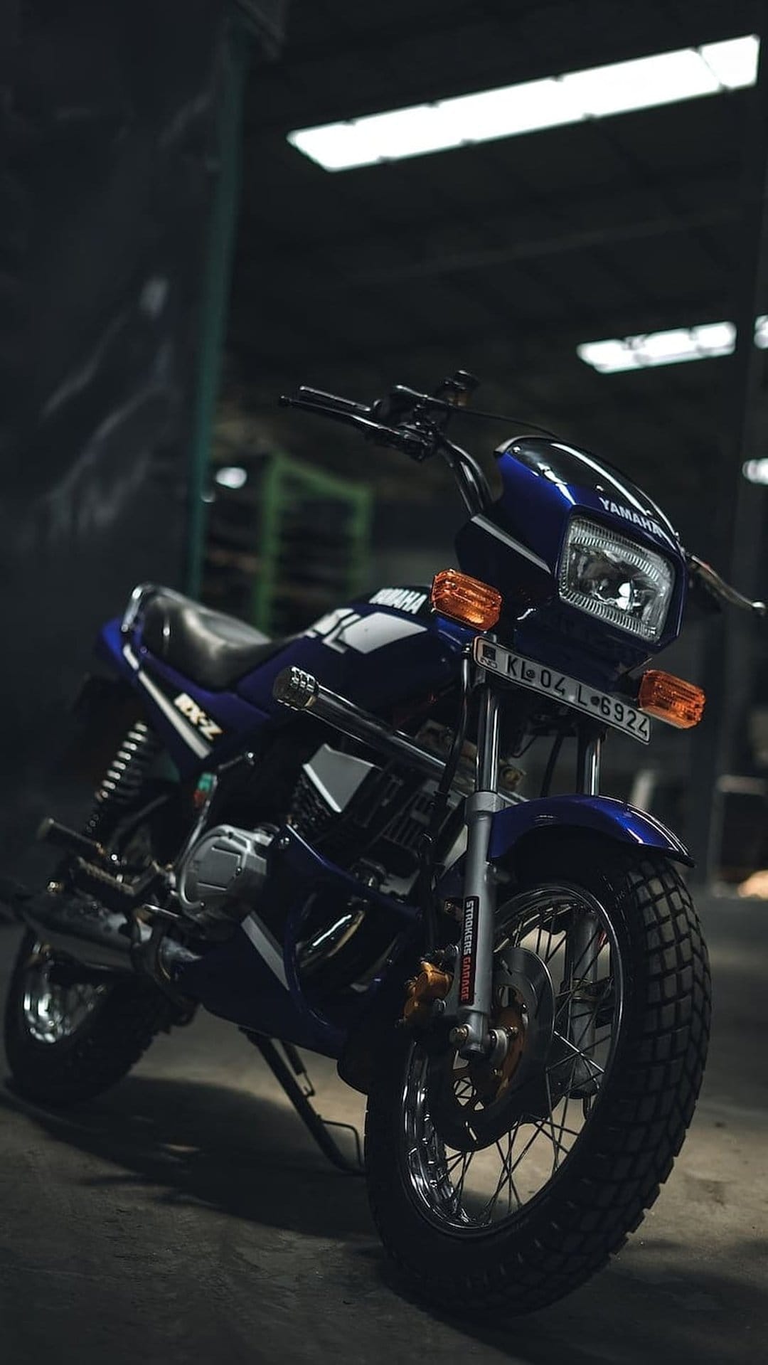 Yamaha RX-Z motorcycle in dark blue parked inside a dimly lit garage with subtle shadows and metallic highlights.