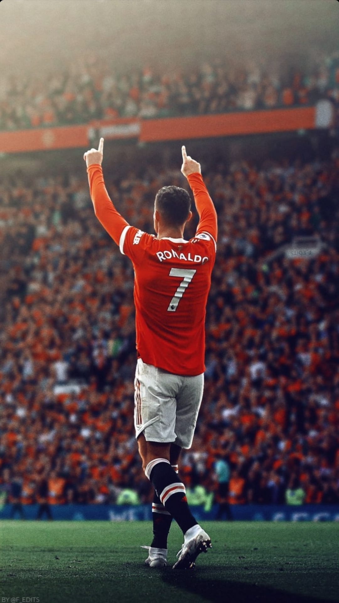 Cristiano Ronaldo raises both arms while pointing upward in a red number 7 jersey during a match celebration.