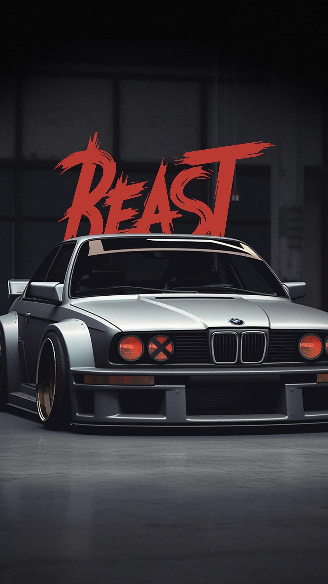 Silver BMW E30 M3 with widebody fenders, orange X-pattern headlights, and red BEAST text in an industrial garage.