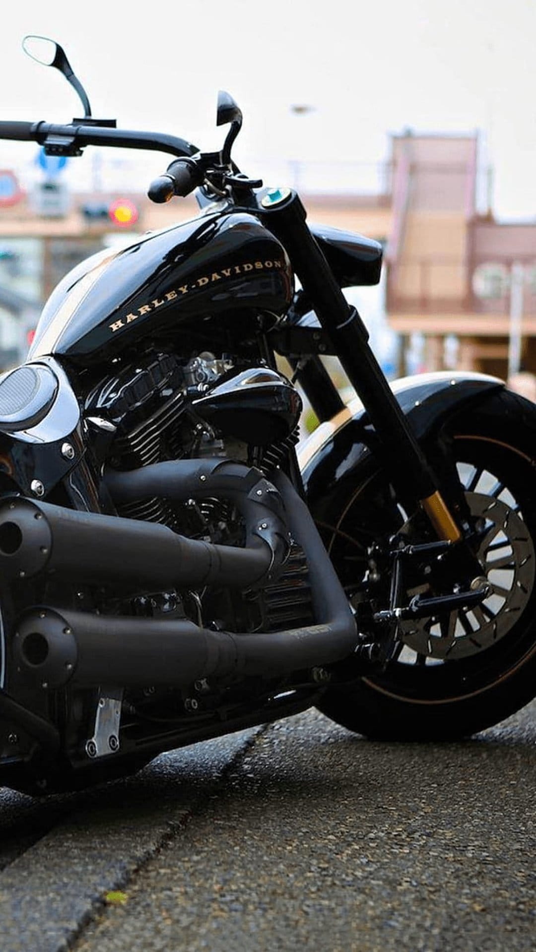 Harley-Davidson motorcycle engine with dual chrome exhaust pipes and black metallic components on a wet street.