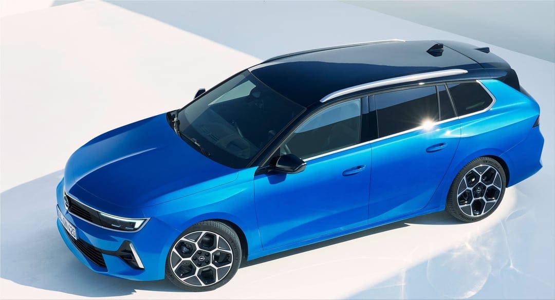Electric blue estate car with a black roof and geometric wheels parked on a white floor in a bright studio.