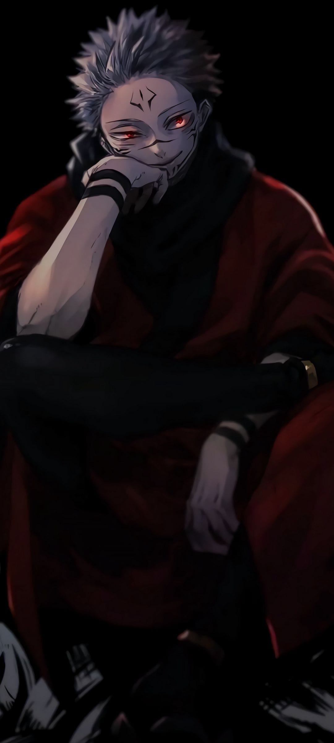 Sukuna wearing a red robe and dark facial markings sits against a black background with glowing red eyes.