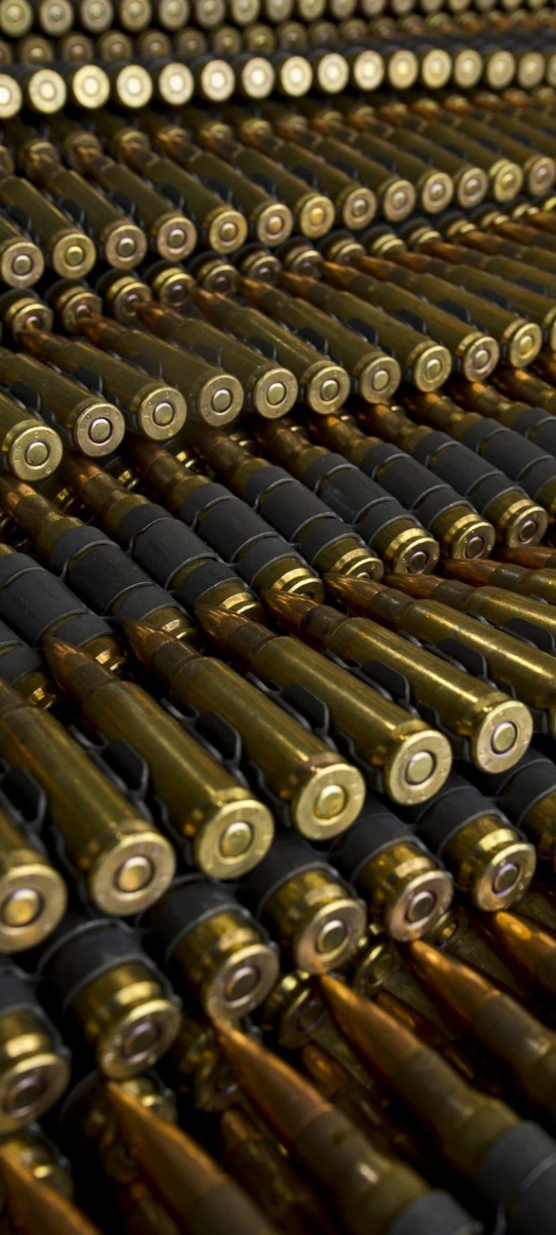 Brass ammunition belts with dark metal links arranged in diagonal rows show a detailed mechanical pattern.