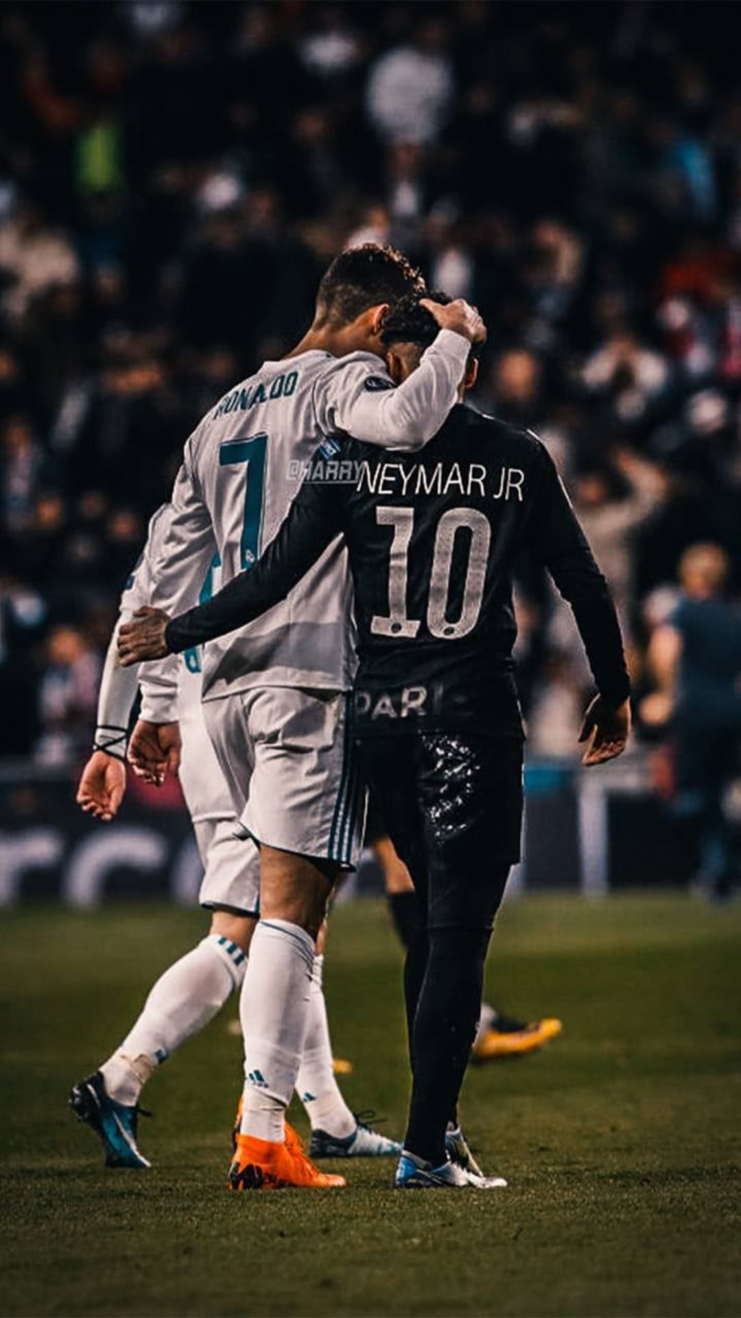 Cristiano Ronaldo walks with his arm around Neymar Jr. on a grass football field during a professional match.