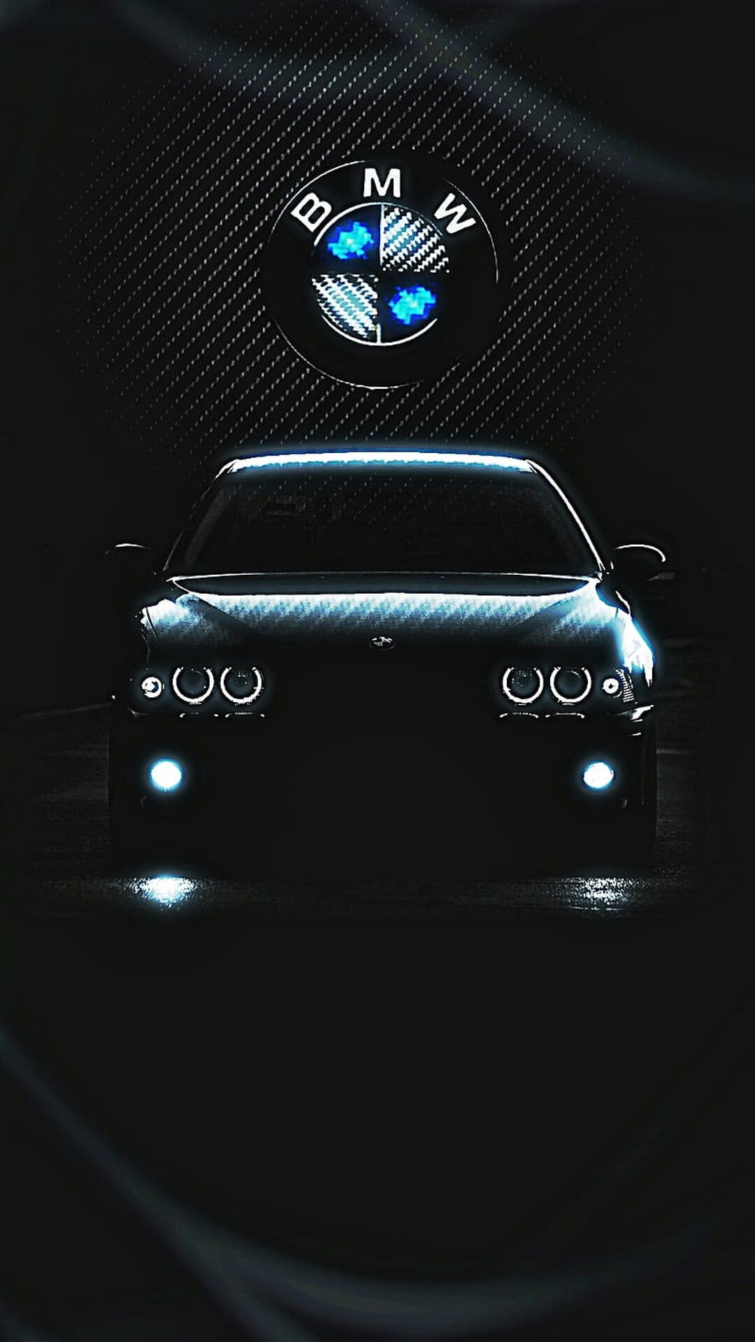BMW front grille with glowing circular headlights and a centered emblem on a dark carbon fiber hood.