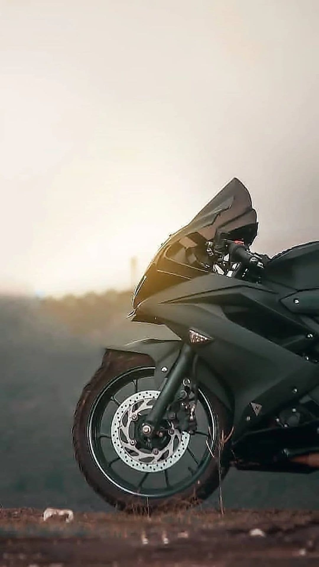 Matte black sportbike front wheel featuring a ventilated disc brake and sleek aerodynamic fairing in sunlight.