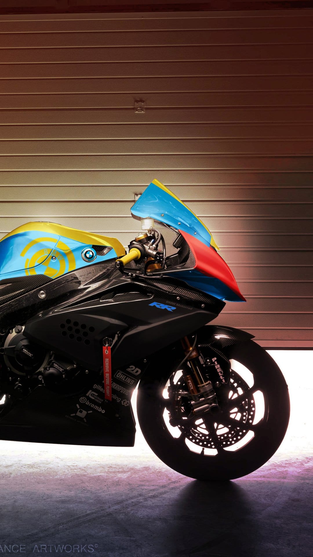 BMW S1000RR motorcycle with blue, yellow, and red fairings parked near a garage with visible Brembo brakes.