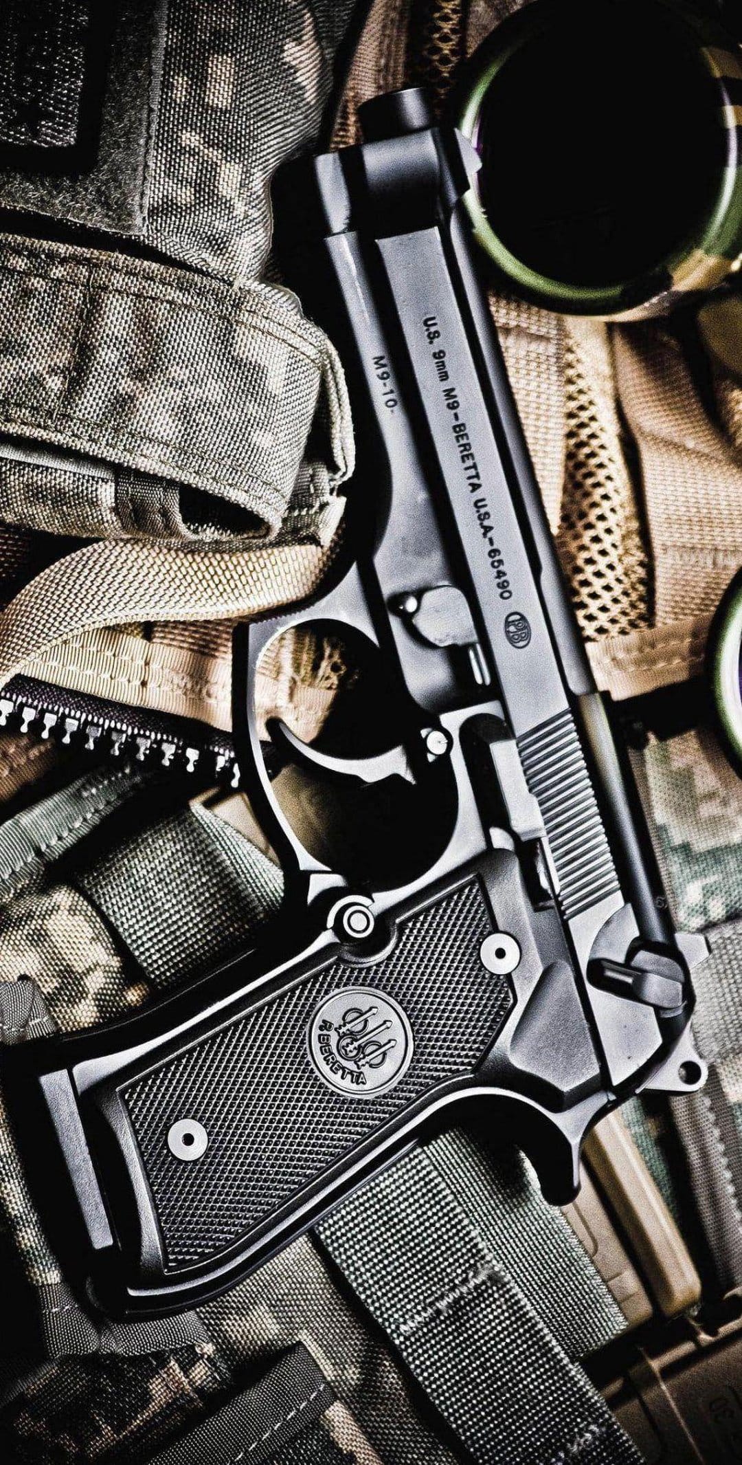 Beretta 92FS 9mm handgun resting on rugged green and brown tactical camouflage fabric with visible metal texture.