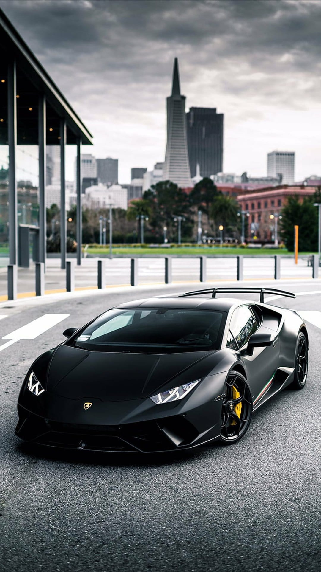 Matte black Lamborghini Huracan with yellow calipers parked before the Transamerica Pyramid in San Francisco.