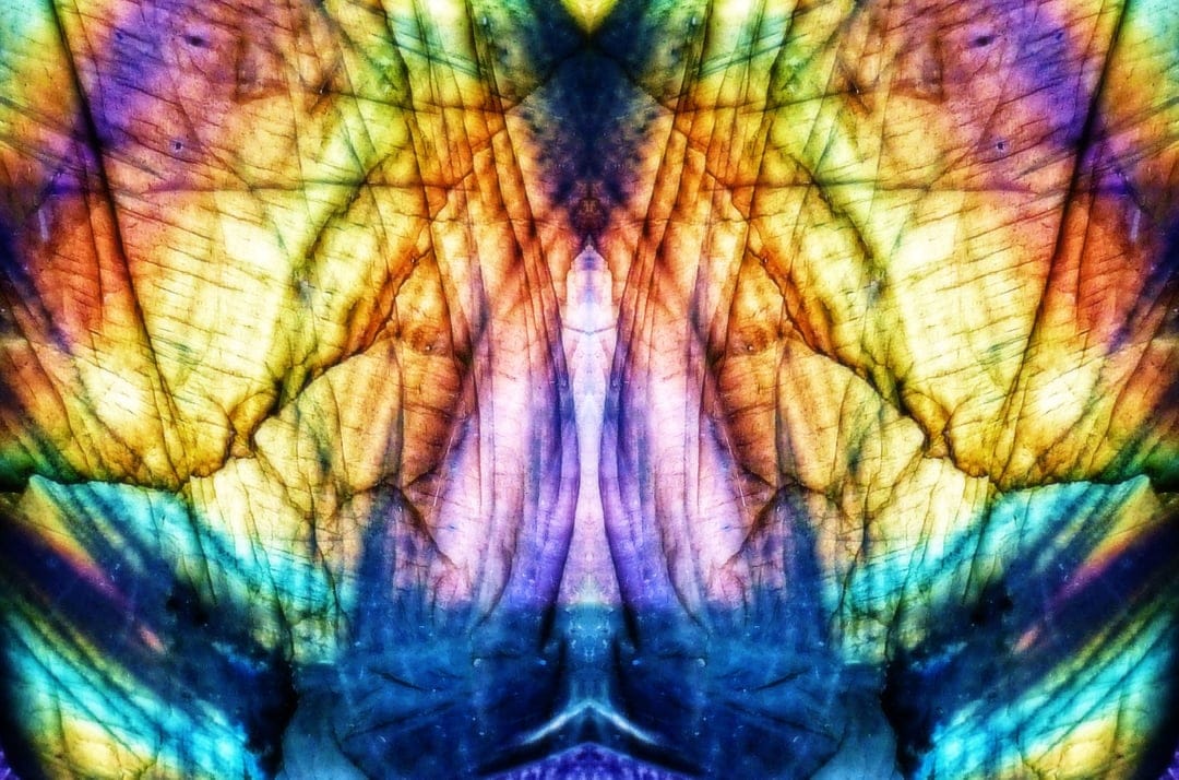 Labradorite gemstone macro showing iridescent blue and purple crystalline fractures with golden light reflections.