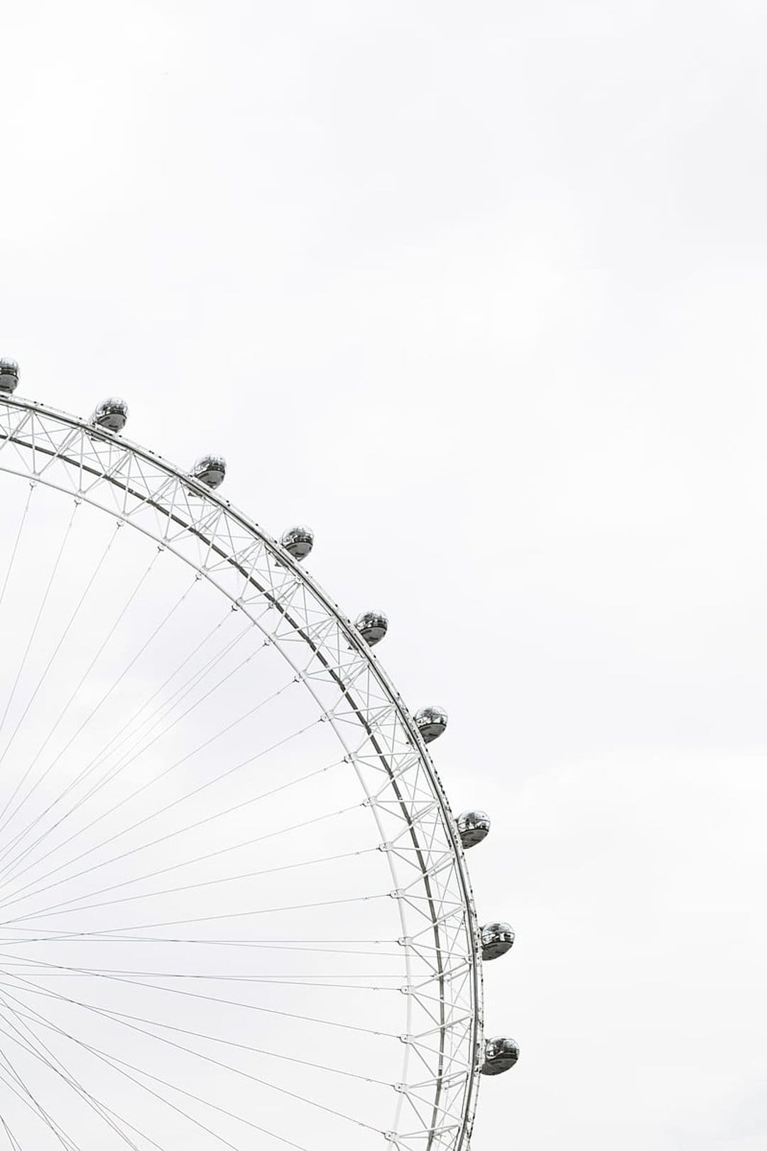 London Eye ferris wheel capsules and spokes against a bright white sky showcase intricate metal engineering.