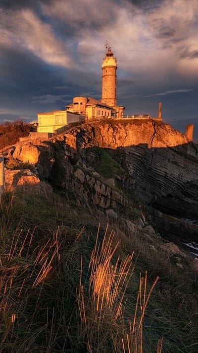Lighthouse, coastal, nature, landscape, peaceful, serene, tranquil, beautiful, outdoor, sunset, sunrise, golden light, dramatic, rocks, ocean, sky, clouds, historic, majestic, beacon