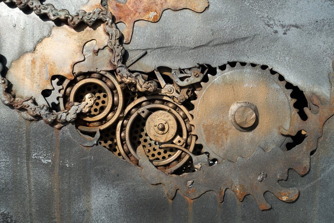 Interlocking rusted iron gears and heavy metallic chains showcase intricate mechanical details in a close-up view.