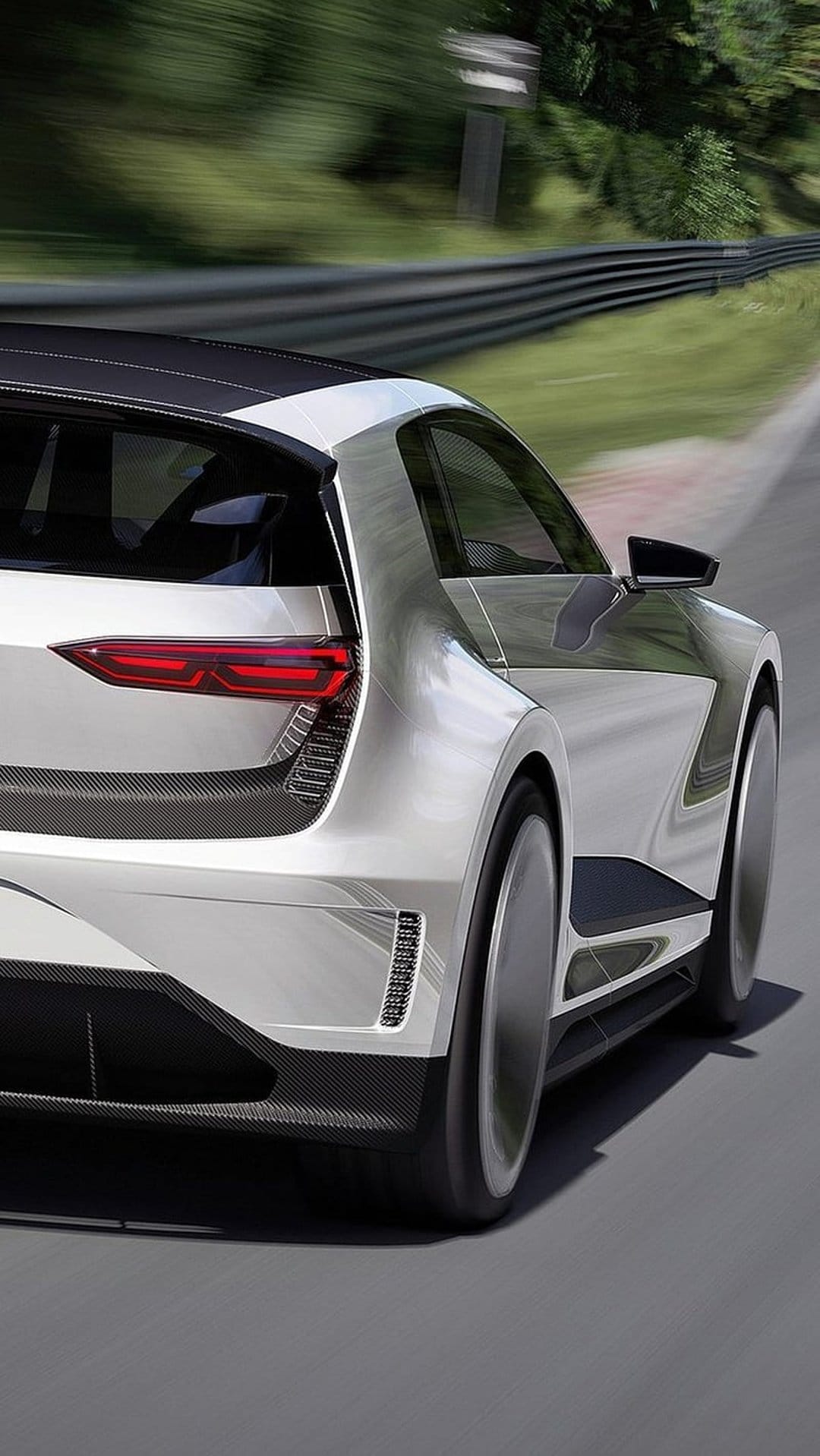 Silver concept car with glowing red LED taillights speeding past a blurred race track background in daylight.
