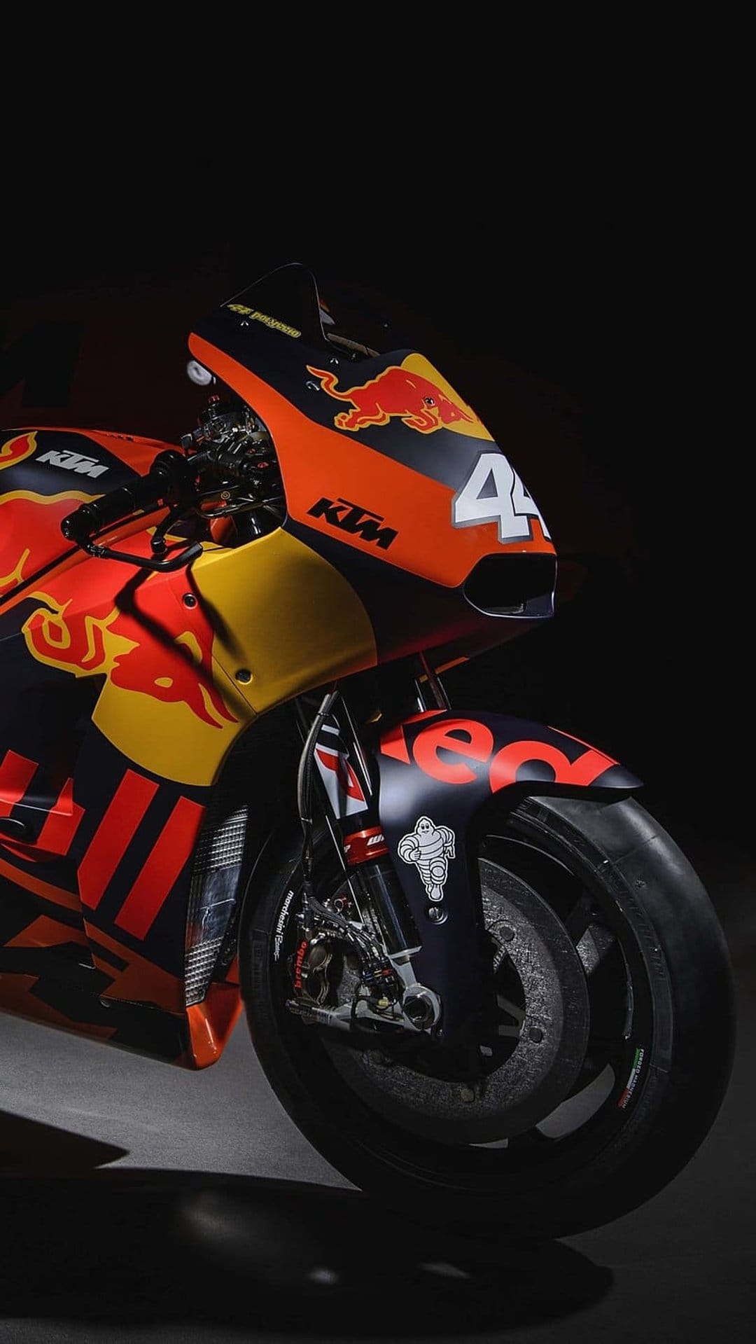 KTM Red Bull racing motorcycle with number 44 displays front wheel mechanics and vibrant orange fairing.